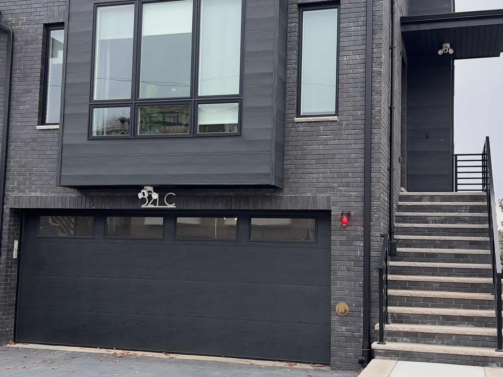 Exterior camera mounted under the eave of a modern dark brick townhouse
