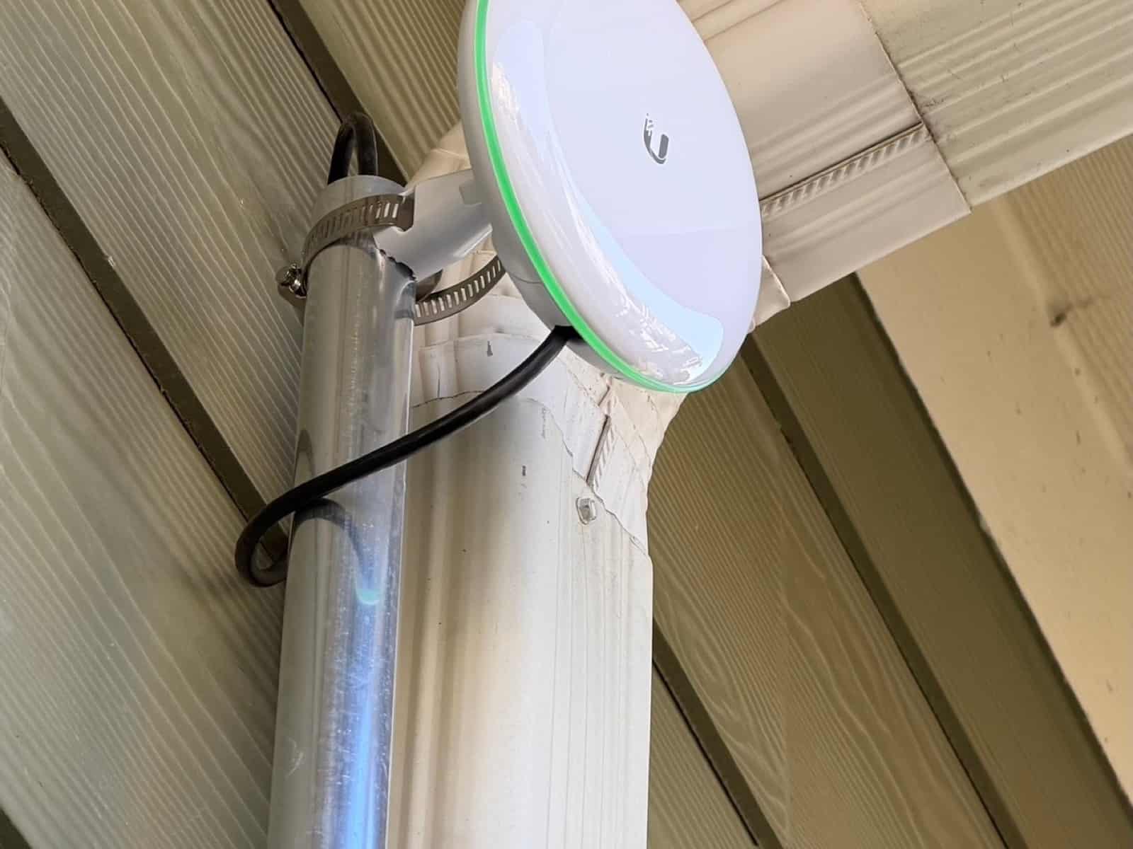 Outdoor wireless access point clamped to a downspout under a building eave