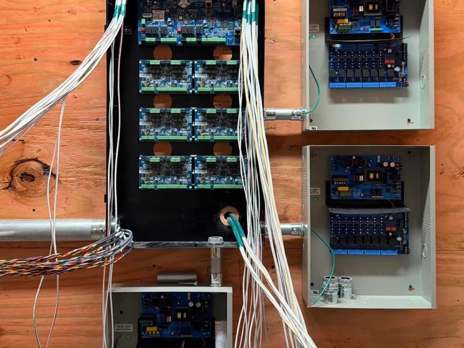 Access control head-end mid-installation with bundles of white door wiring being landed on the boards