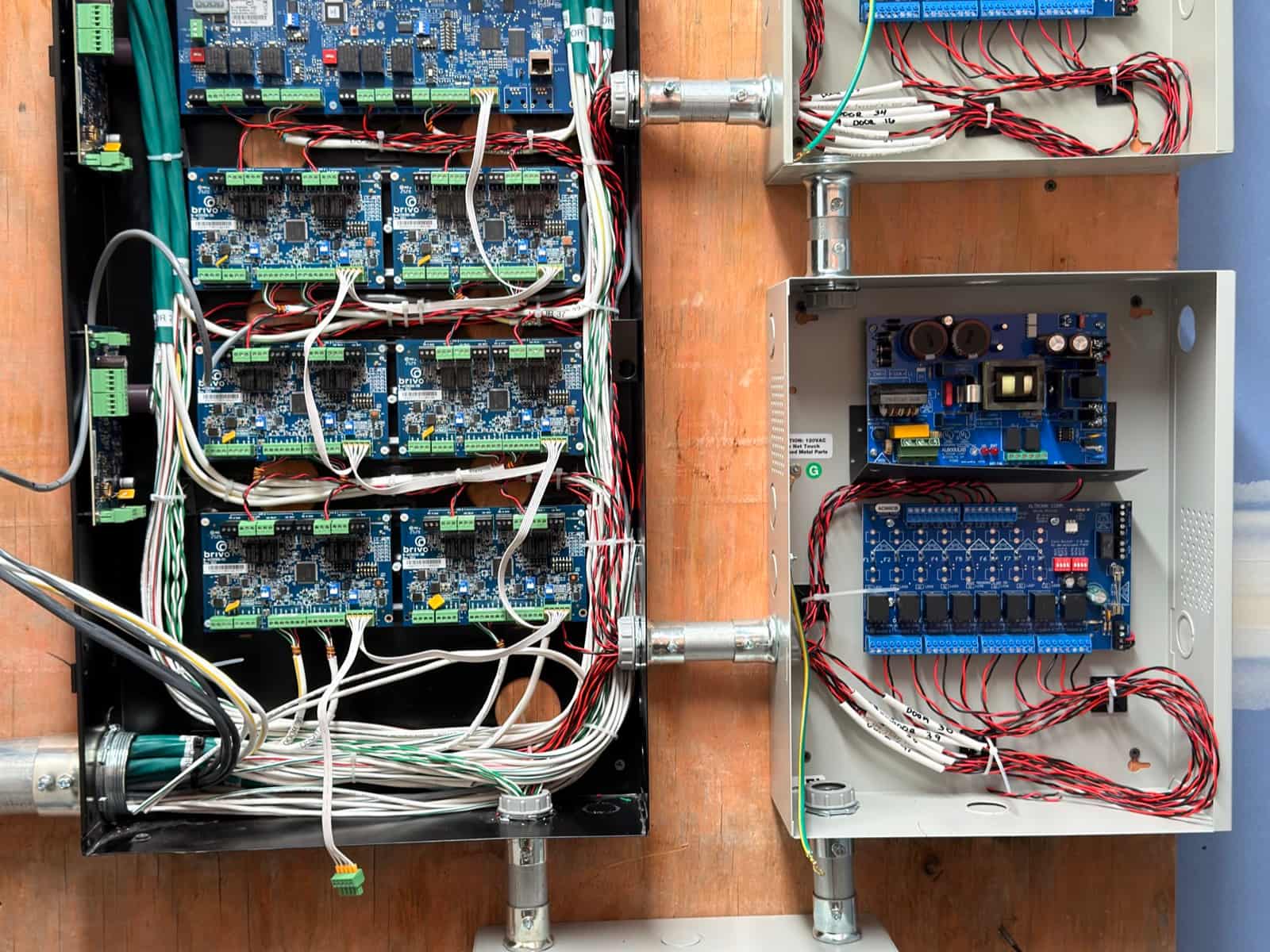 Access control panel with multiple door boards wired out to separate power supply enclosures on a plywood backboard