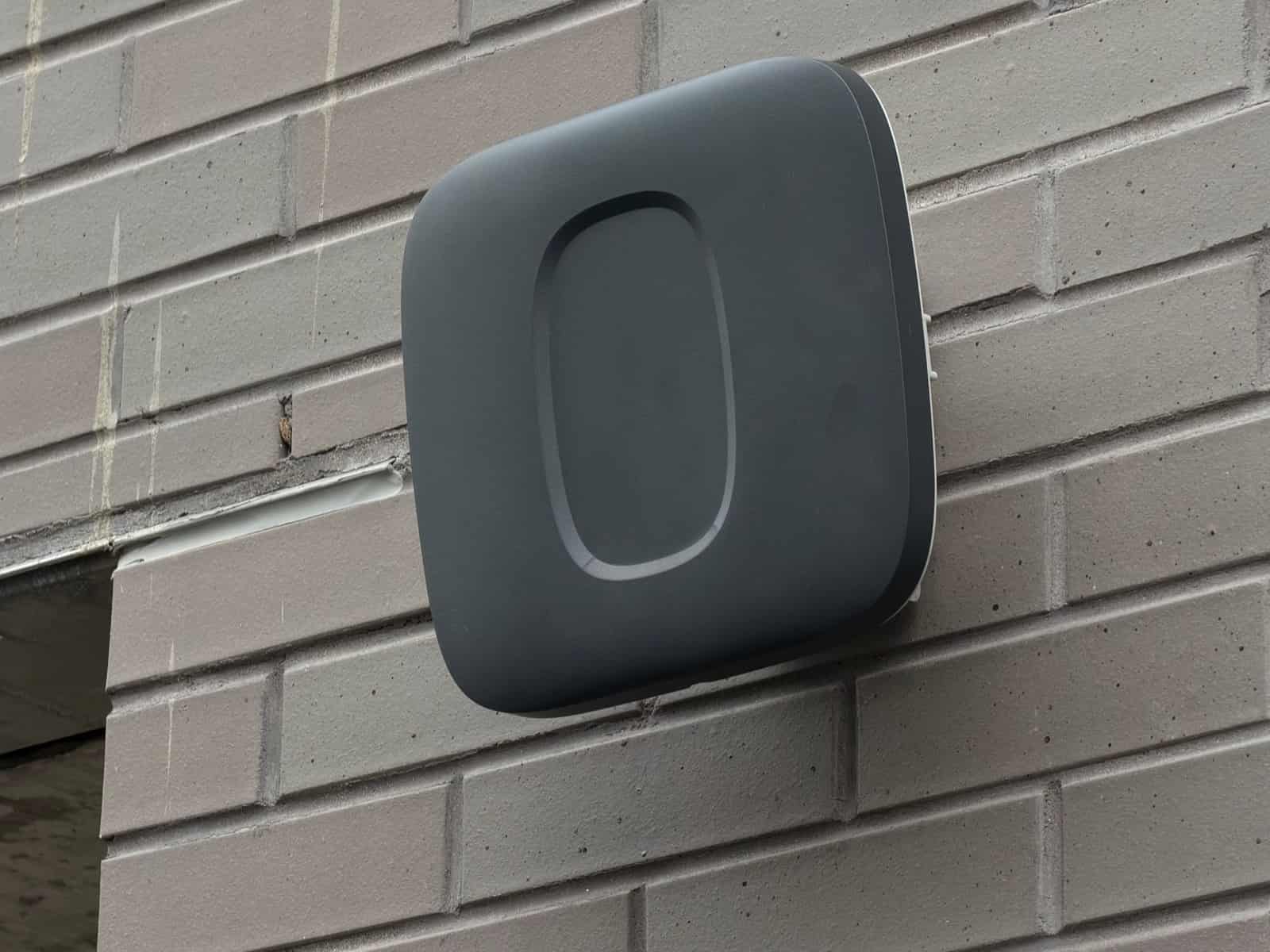 Wireless access point mounted on an exterior brick wall above a doorway